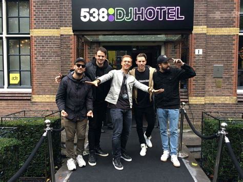 Four Men Posing In Front Of A Hotel