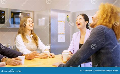 Coworkers Laughing While Drinking Coffee During Break In The Office