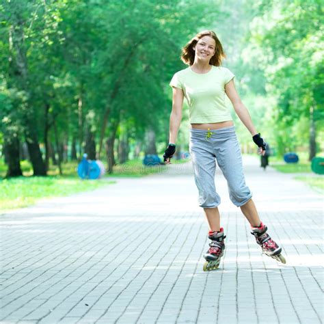 Menina Desportiva Da Patinagem De Rolo No Parque Que Rollerblading No