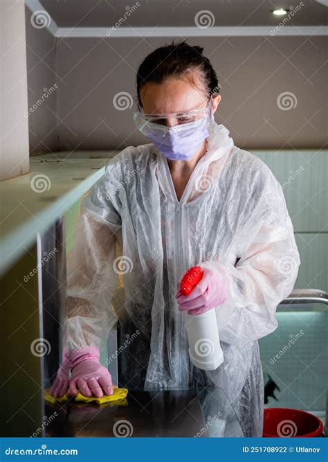 A Worker In A Protective Suit Cleans The Shelves In The Kitchen With A