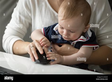 Closeup Photo Of Cute Baby Boy Sitting On Mothers Lap And Playing With