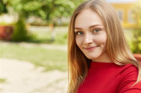 Jolie jeune fille blonde aux yeux verts lèvres minces fossettes sur les joues et taches de