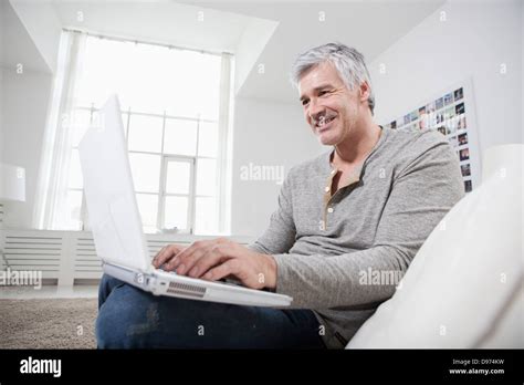 Germany Bavaria Munich Mature Man Using Laptop On Couch Smiling