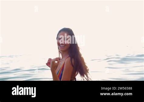 Beautiful Girl In A Bikini Has Fun In The Water At Sunset And Asks To Follow Her Partner With