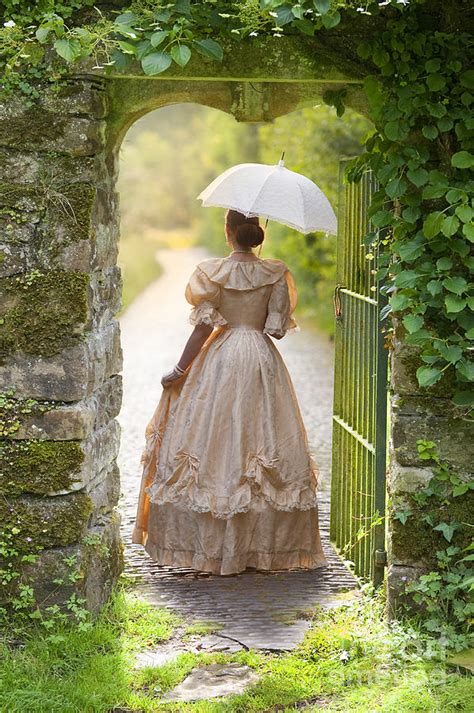 Victorian Woman With Parasol Walking Through A Pretty Gateway