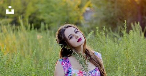 Woman In Blue Pink And Green Floral Sleeveless Dress Standing On Green Grass Field During