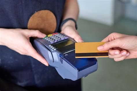 Manos De Asistente De Tienda Con Lector De Tarjetas Durante El Pago Sin