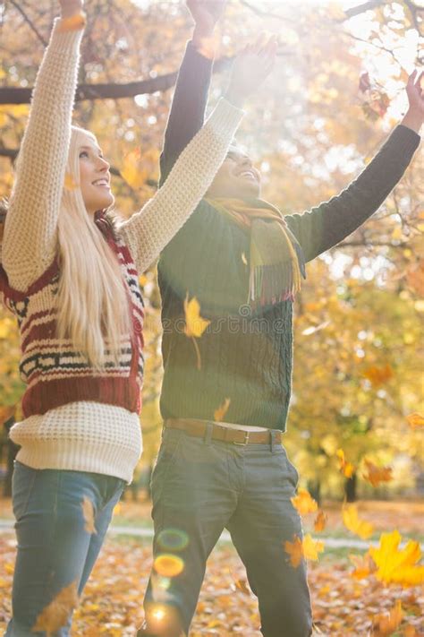 Young Couple Enjoying Falling Autumn Leaves In Park Stock Photo Image