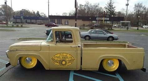 An Old Yellow Truck Parked In A Parking Lot