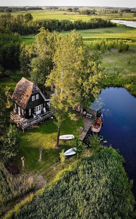 An Aerial View Of A House With Boats In The Water And Trees Around It