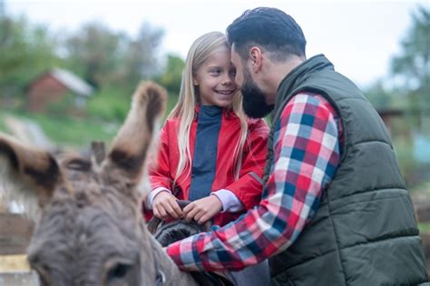 Premium Photo On A Farm A Cute Blonde Girl Riding A Donkey On A Farm