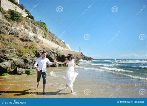 Happy Couple Running On The Beach Near Sea In Wedding Day Stock Image