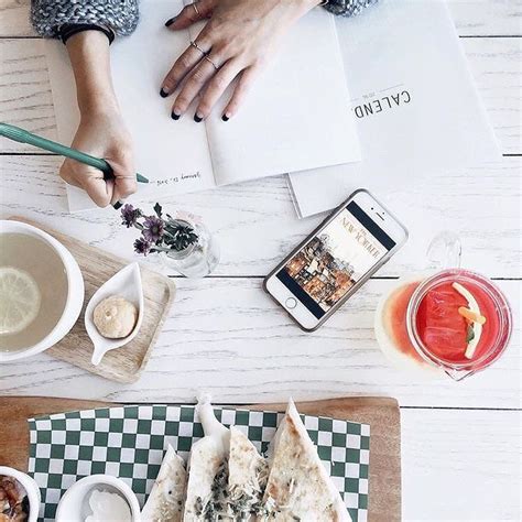 Two People Are Sitting At A Table With Food And Drinks On It One Is