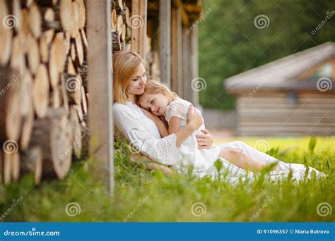 El Blonde Hermoso De La Madre En El Vestido Blanco Abraza Blando Su Dau Imagen De Archivo