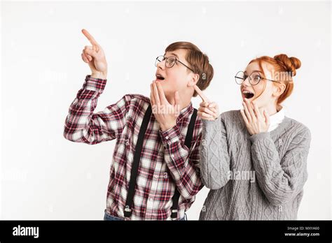 Excited Couple Of School Nerds Pointing Fingers Away At Copy Space Isolated Over White