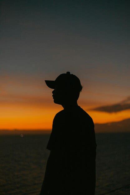 Premium Photo A Man Standing In Front Of The Ocean At Sunset