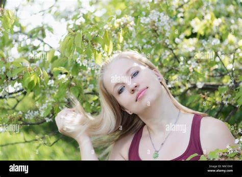 Lächelnde junge blonde Frau ist ein Blick auf Kamera und mit einem schiefen Kopf gespielt