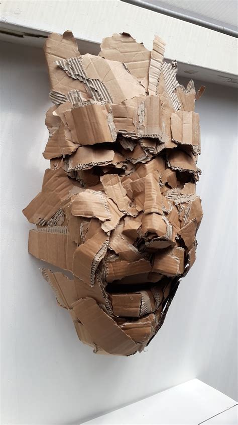 a mask made out of cardboard sitting on top of a wall