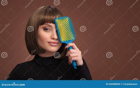 Une Jeune Fille Souriante Avec Une Coupe De Cheveux Au Bob Tient Un