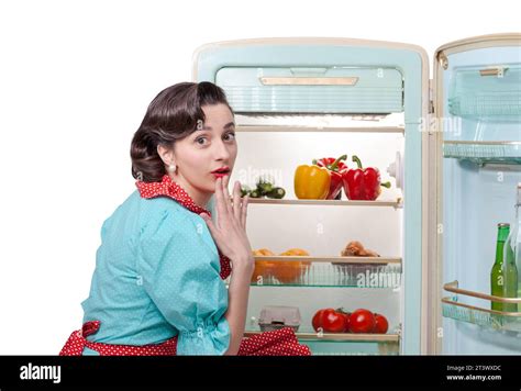 Vintage Style Housewife In The Kitchen Preparing Lunch She Is Opening The Fridge And Looking At