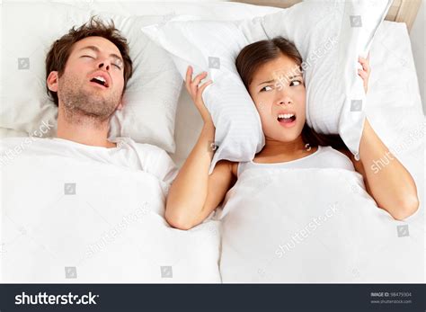 Snoring Man Couple In Bed Man Snoring And Woman Can Not Sleep Covering Ears With Pillow For