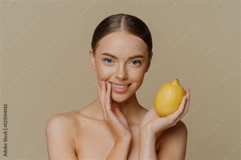 Portrait Of Charming Half Naked Woman With Dark Combed Hair Holds Fresh Whole Lemon Uses Fruit