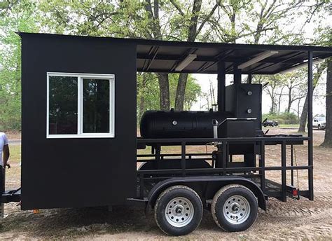 A Man Standing Next To A Black Trailer With A Bbq On Its Side