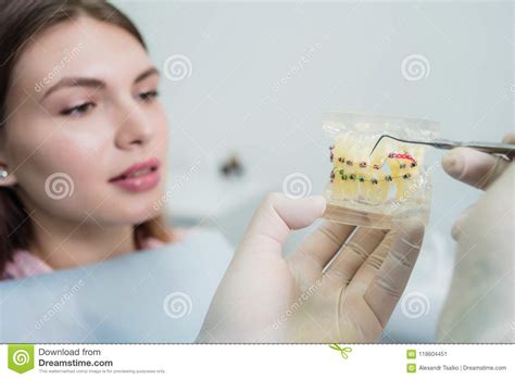 Doctor Orthodontist Explains To The Patient How The Braces Are Arranged