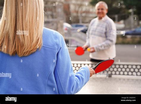 Mature Couple Holding Table Tennis Ball And Rackets In The Garden Stock