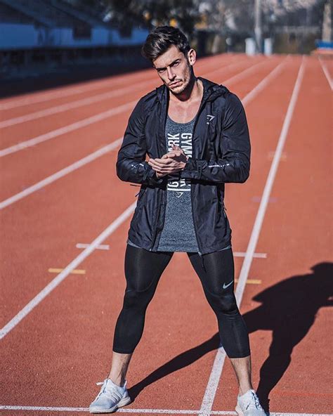 A Man Standing On A Track Looking At His Cell Phone While Wearing Leggings