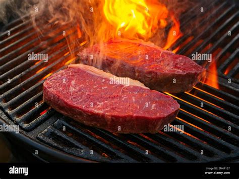 Raw Dry Aged Wagyu Roast Beef Steak Grilled As Close Up On A Charcoal Grill With Fire And Smoke