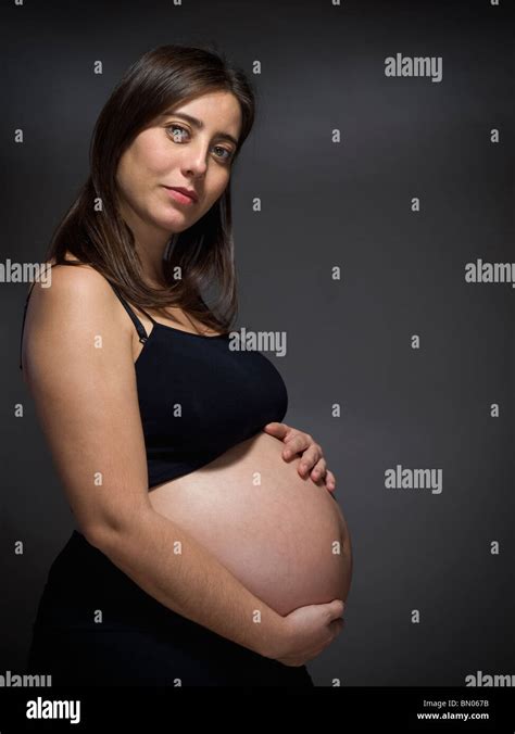 Une Femme Enceinte Tient Son Gros Ventre Sur Un Fond Gris Photo Stock