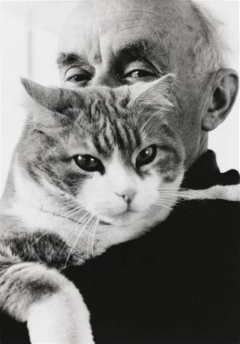 an old man is holding a cat in his arms while he looks at the camera