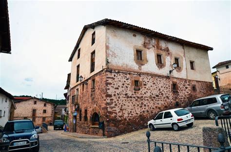 Two Cars Are Parked In Front Of An Old Building With Rusted Paint On It