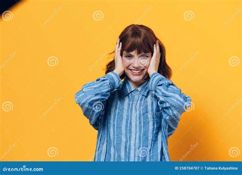 A Happy Emotional Woman Smiles Broadly With Her Hands On Her Head Standing On A Yellow