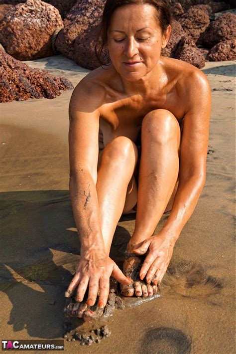 Naked Older Woman Diana Ananta Covers Her Feet In Beach Sand At Low