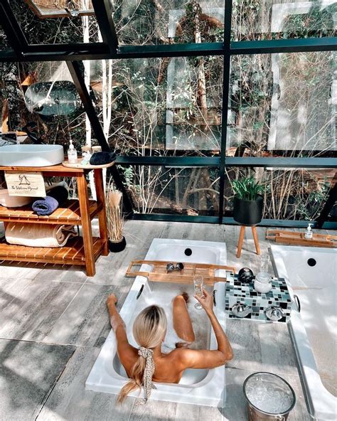 A Naked Woman Sitting In A Bathtub On Top Of A Tiled Floor Next To A Window