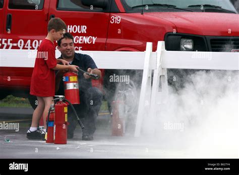 A little boy learning how to use an extinguisher at a Fire Safety Fair ...