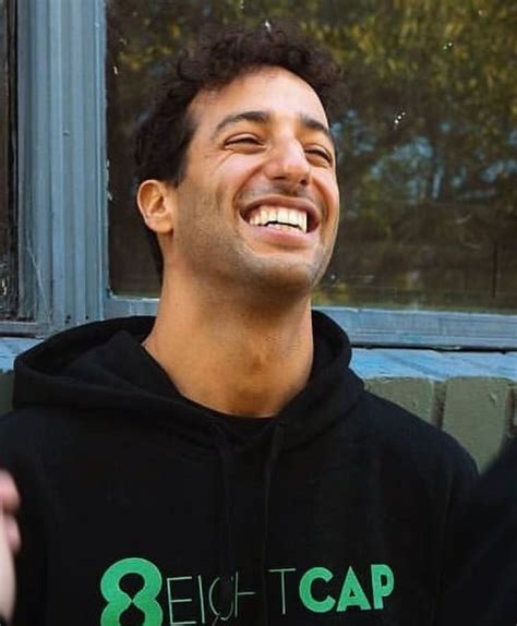 a man with curly hair wearing a black hoodie smiles at the camera while ...