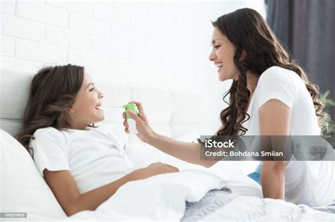 Young Beautiful Mother Spraying Medicine Into Daughters Sick Sore