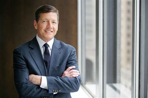 A Man Wearing A Suit And Tie Standing In Front Of A Window With His