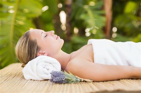 Premium Photo Peaceful Blonde Lying On Bamboo Mat With Flowers