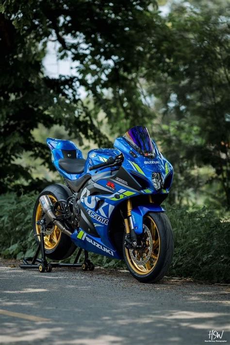 A Blue And Yellow Motorcycle Parked On The Side Of A Road Next To Some