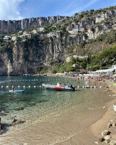 The Beach Is Crowded With People And Boats In The Clear Blue Water