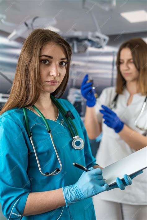 Retrato De Dos Jóvenes Enfermeras Con Ropa Médica Y Sonriendo En El Quirófano Foto Premium