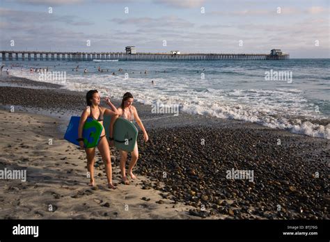 Two Girls Enjoy Boogie Boarding On The Beach Oceanside California