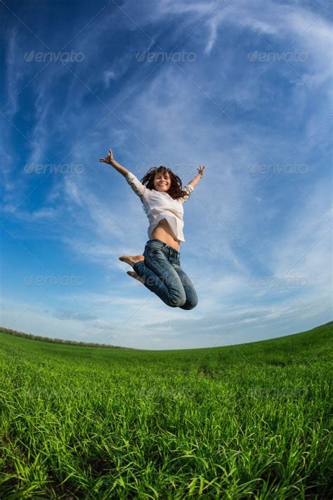 A Woman Jumping In The Air On Top Of A Green Field