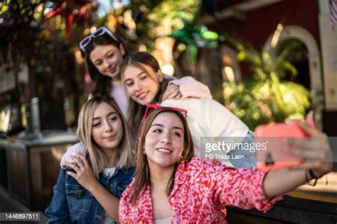 Young Women Taking Selfies Or Filming Using Mobile Phone Outdoors High