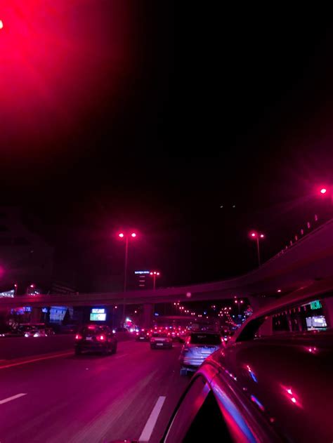 Cars Driving Down The Road At Night With Red Lights In The Dark Sky