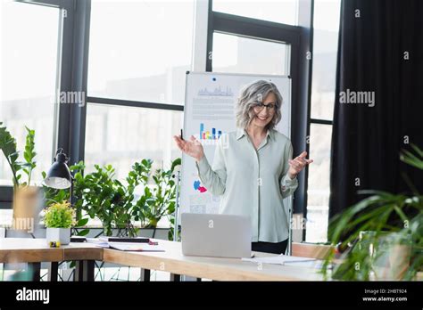 Happy Mature Businesswoman Having Video Call On Laptop Near Flip Chart In Office Stock Photo Alamy